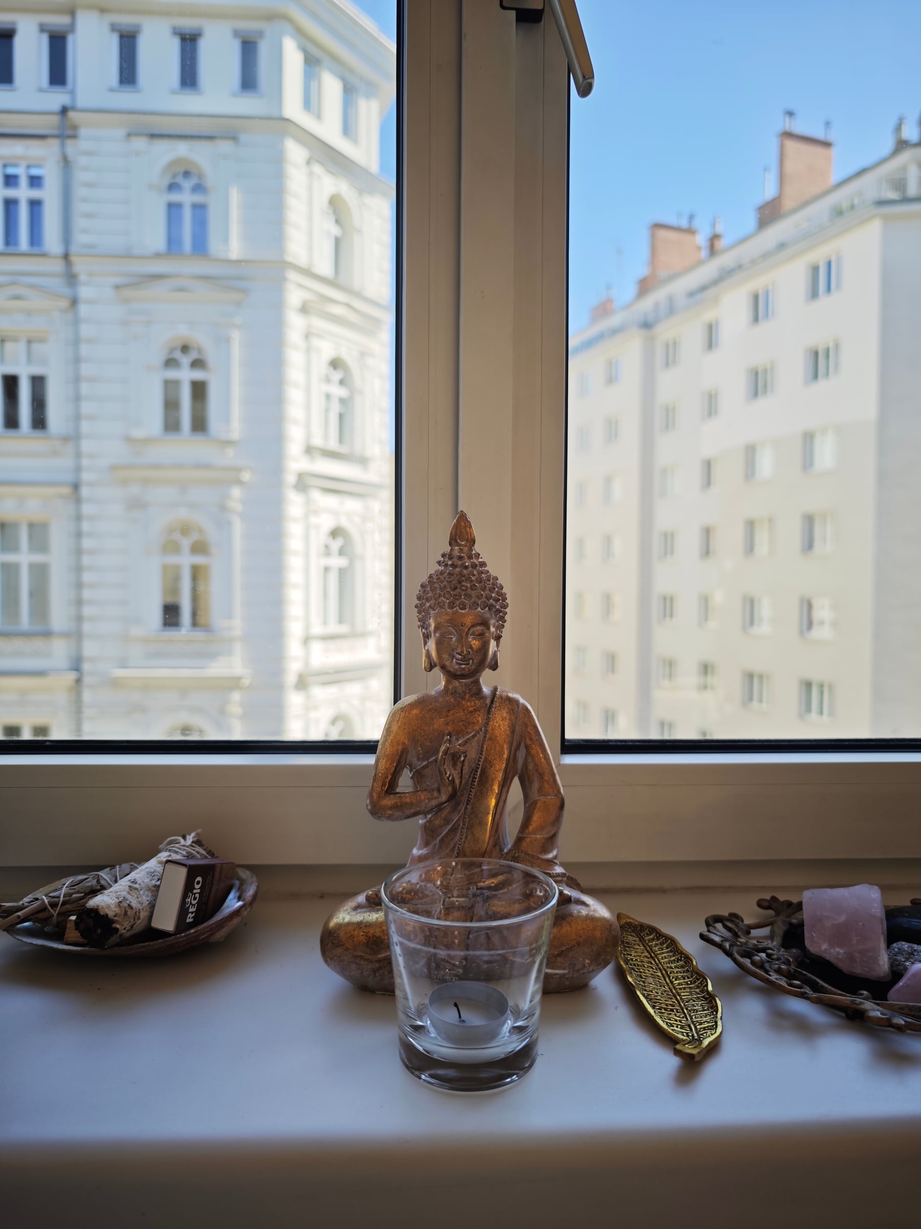 A bronze meditation figure in a bright Vienna window